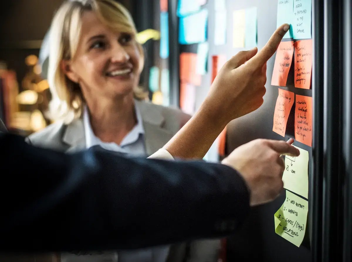 Equipe analisando etapas da jornada de compra B2B em um quadro com post-its, representando planejamento estratégico, alinhamento entre áreas e definição de ações para geração e conversão de leads.