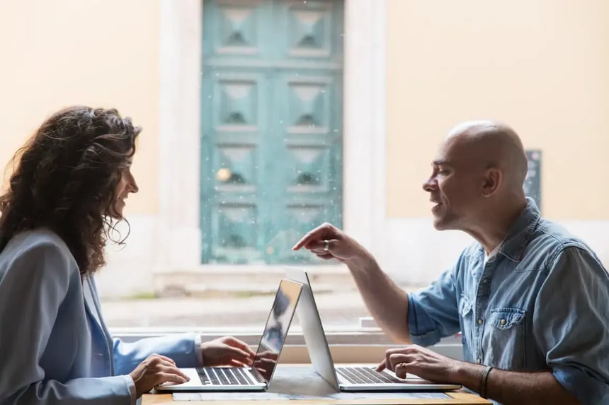 Profissionais debatendo ideias em frente a notebooks, representando colaboração, repertório cultural e o fator humano na criação em tempos de IA.